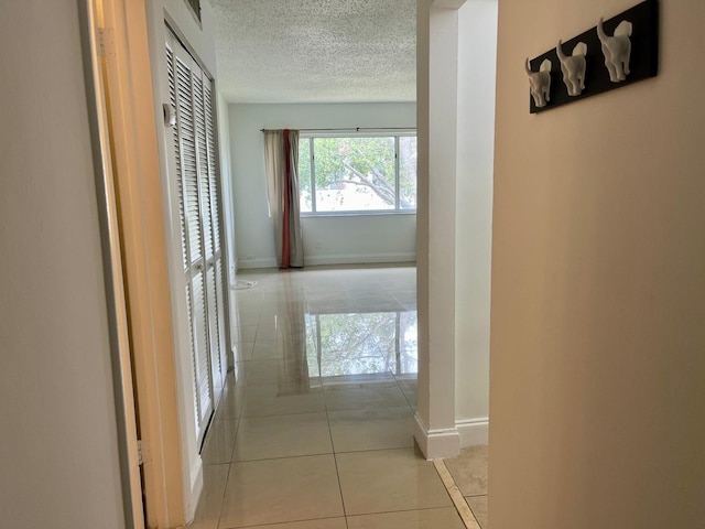 hallway featuring light tile patterned floors and a textured ceiling