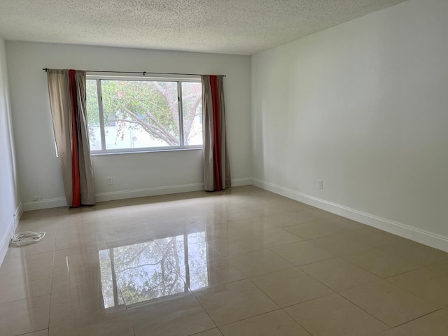 tiled empty room featuring a textured ceiling