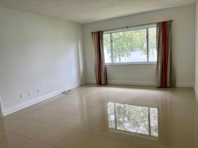 tiled empty room featuring a healthy amount of sunlight and a textured ceiling