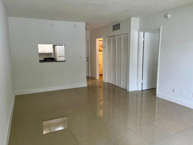 unfurnished room with light tile patterned floors and a textured ceiling