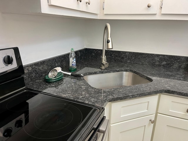 interior details featuring electric stove, sink, and dark stone counters