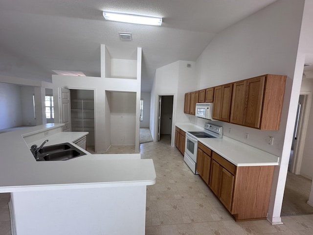 kitchen with kitchen peninsula, white appliances, vaulted ceiling, and sink