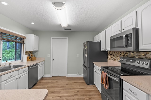 kitchen with white cabinets, decorative backsplash, stainless steel appliances, and a textured ceiling