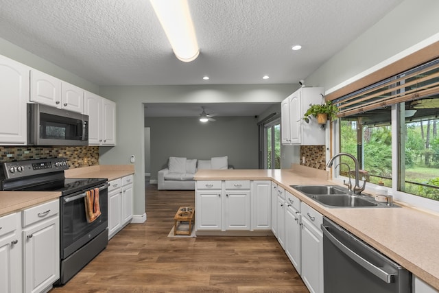 kitchen with kitchen peninsula, appliances with stainless steel finishes, decorative backsplash, sink, and white cabinets