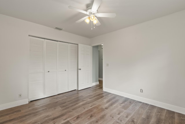 unfurnished bedroom featuring ceiling fan, a closet, and hardwood / wood-style floors