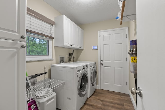 clothes washing area with washing machine and dryer, cabinets, dark wood-type flooring, and a textured ceiling