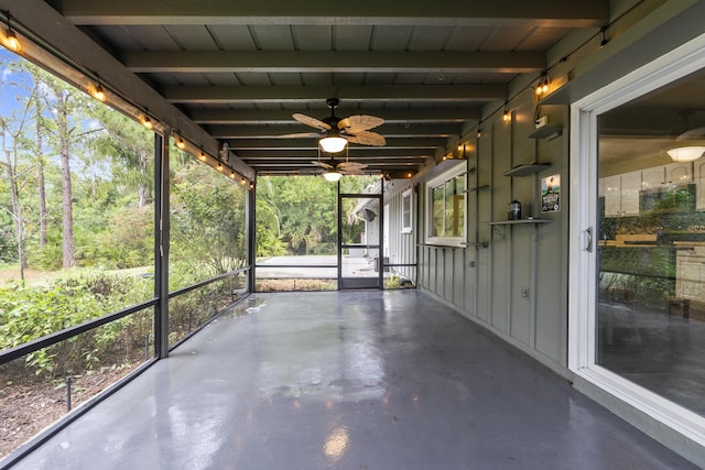 unfurnished sunroom featuring beamed ceiling and a wealth of natural light