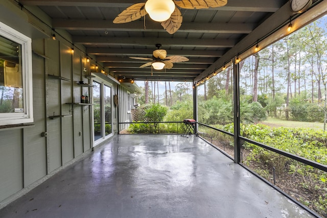 unfurnished sunroom featuring beam ceiling and ceiling fan