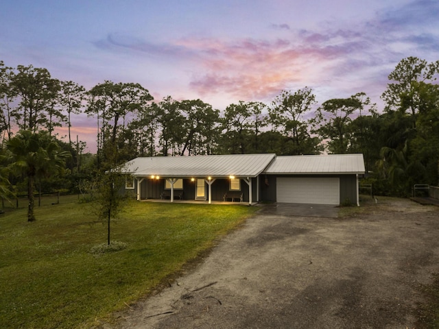 single story home featuring covered porch, a garage, and a yard