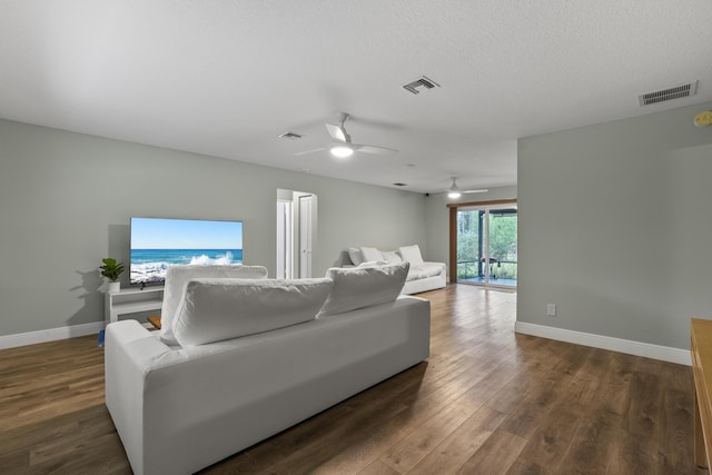 living room featuring ceiling fan, dark hardwood / wood-style floors, and a textured ceiling