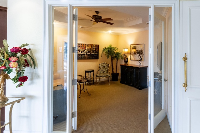 hall featuring carpet flooring, a tray ceiling, and crown molding