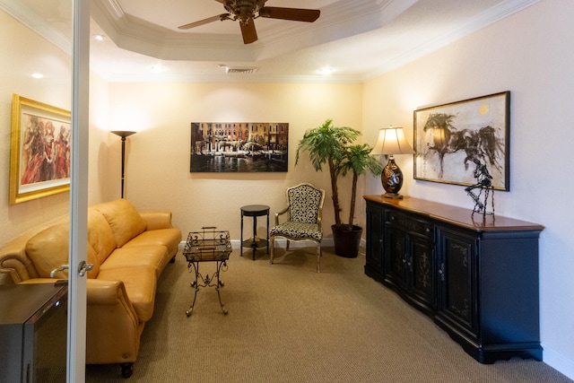 living area featuring a tray ceiling, crown molding, carpet, and ceiling fan