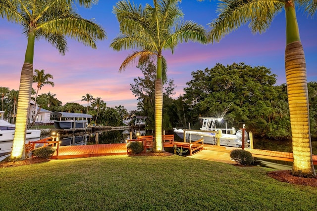 view of property's community featuring a water view, a lawn, and a boat dock