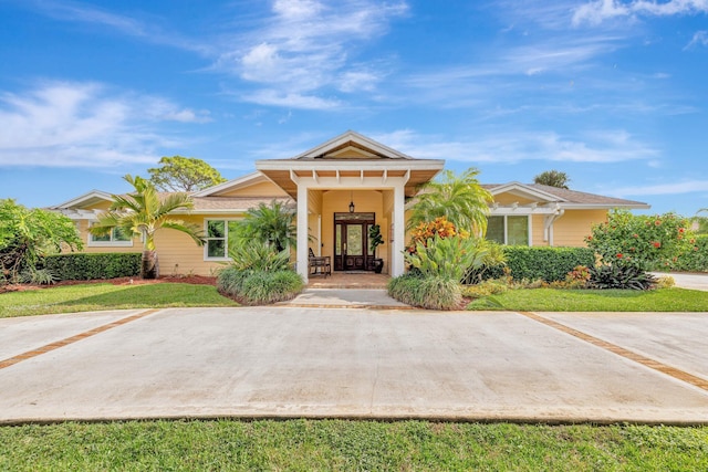 view of front of home with covered porch, a front yard, and french doors