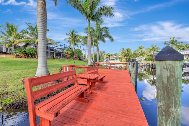 view of dock with a water view, a lanai, and a lawn