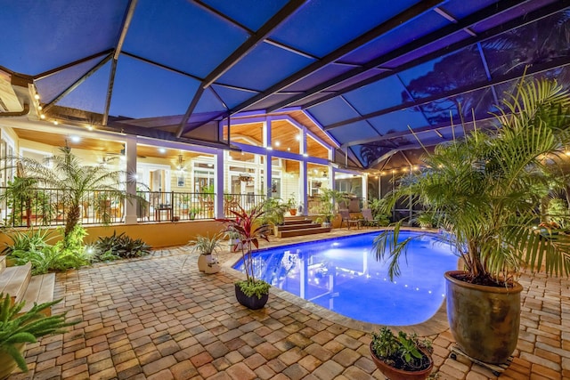 view of swimming pool with glass enclosure, ceiling fan, and a patio