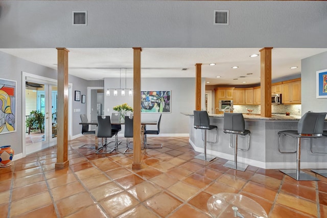 kitchen with a breakfast bar, light brown cabinets, decorative backsplash, appliances with stainless steel finishes, and kitchen peninsula