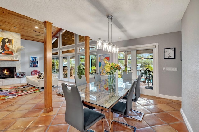 dining room with a stone fireplace, wooden ceiling, a textured ceiling, and french doors