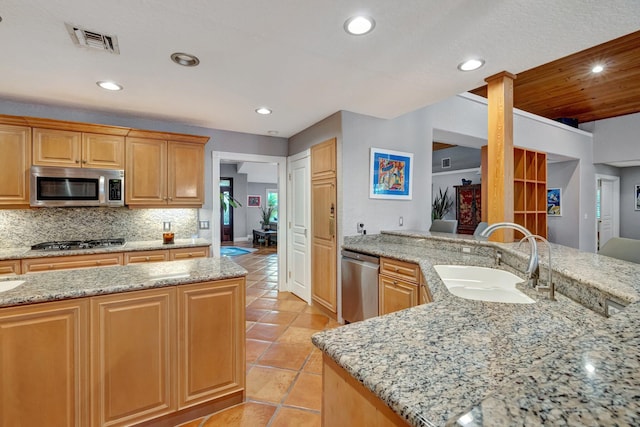 kitchen with light stone countertops, appliances with stainless steel finishes, an island with sink, and sink