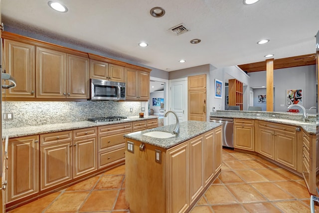 kitchen featuring backsplash, sink, a center island with sink, and appliances with stainless steel finishes