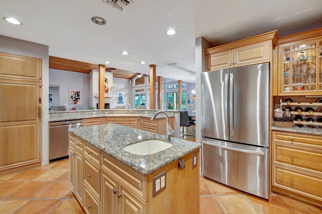 kitchen featuring light stone counters, a center island, sink, and stainless steel appliances