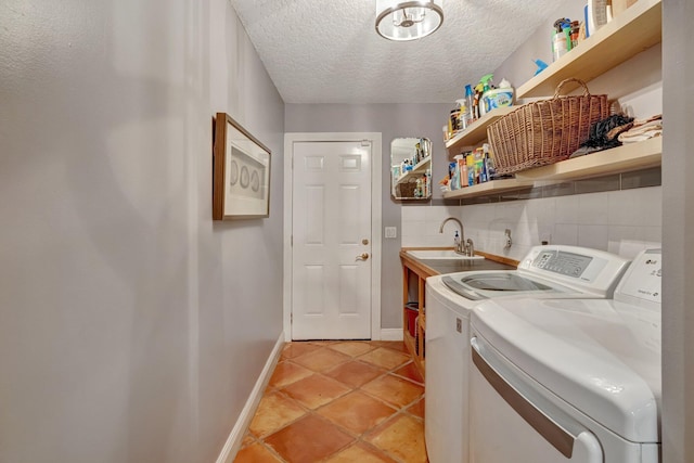 washroom featuring light tile patterned flooring, a textured ceiling, washing machine and dryer, and sink