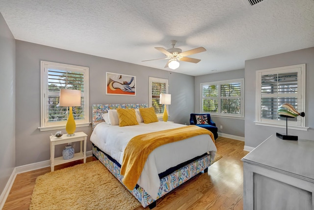 bedroom featuring a textured ceiling, light wood-type flooring, and ceiling fan