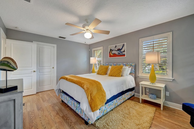 bedroom featuring multiple windows, light hardwood / wood-style floors, and ceiling fan