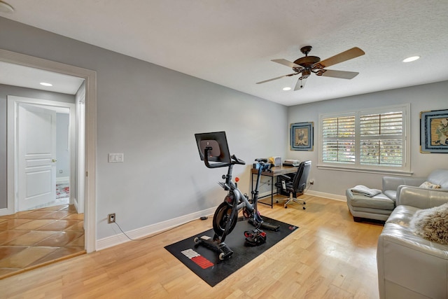 workout room featuring ceiling fan, hardwood / wood-style floors, and a textured ceiling