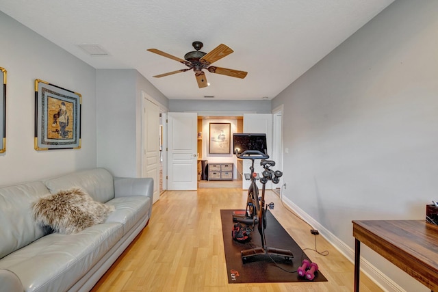 workout area with ceiling fan and light wood-type flooring