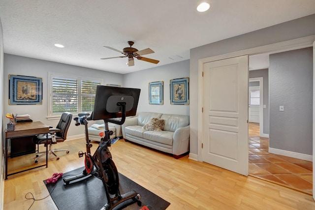 workout room with a textured ceiling, light hardwood / wood-style floors, and ceiling fan