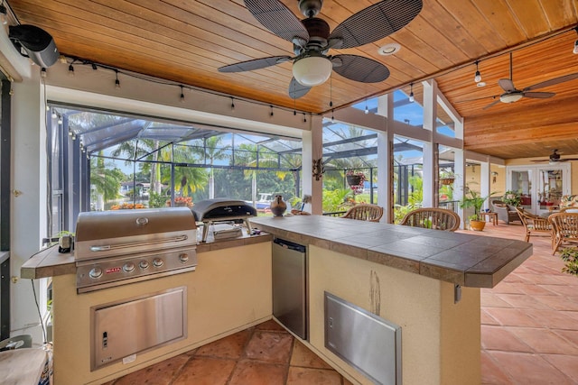 view of patio featuring glass enclosure, a bar, and grilling area