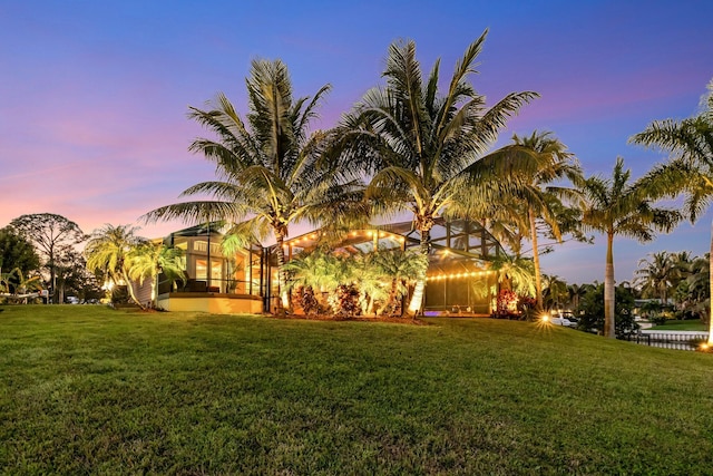 yard at dusk featuring a lanai