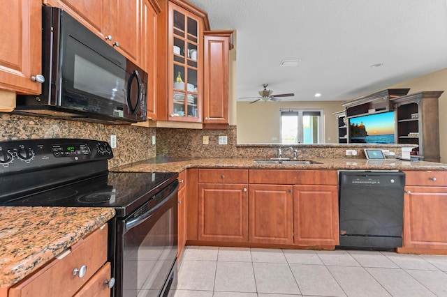 kitchen with sink, light stone counters, backsplash, light tile patterned floors, and black appliances