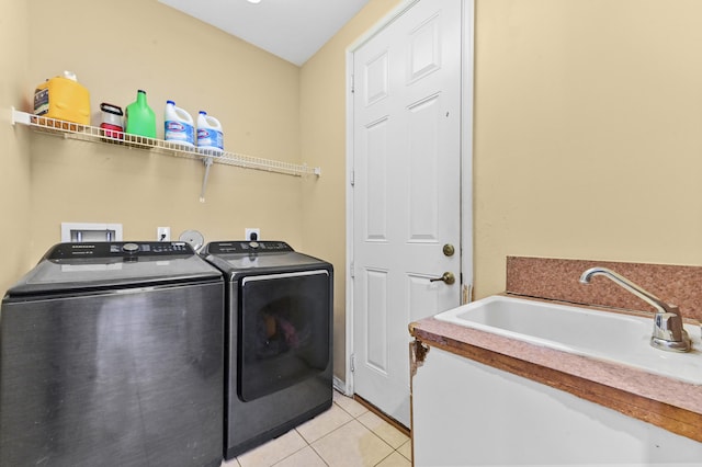 clothes washing area featuring washer and dryer, light tile patterned floors, and sink