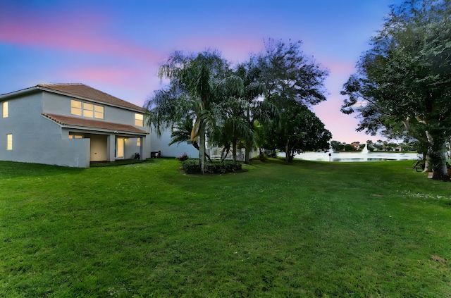 yard at dusk featuring a water view