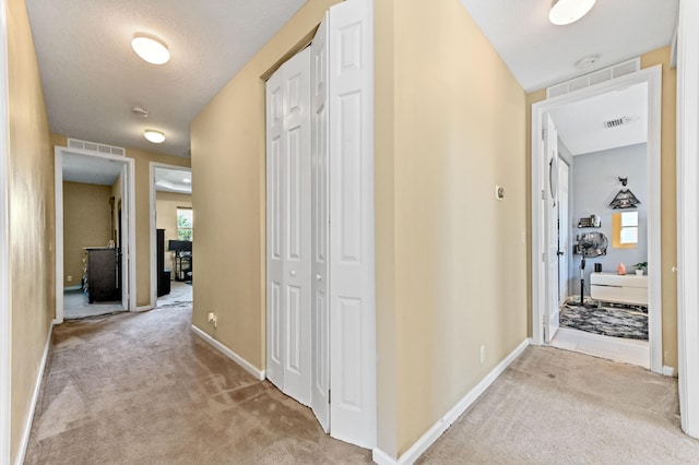 hallway featuring light colored carpet