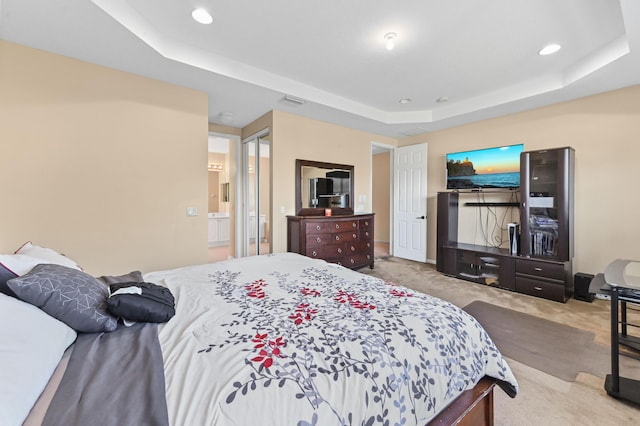 carpeted bedroom featuring a raised ceiling and connected bathroom