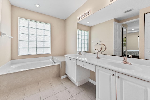 bathroom with tile patterned floors, vanity, and a relaxing tiled tub