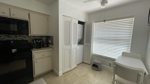 kitchen with stacked washer and clothes dryer, black appliances, white cabinets, decorative backsplash, and light tile patterned flooring