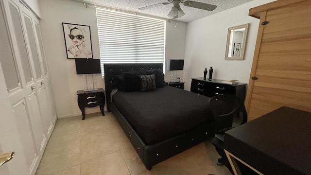 bedroom with ceiling fan, light tile patterned floors, a textured ceiling, and a closet