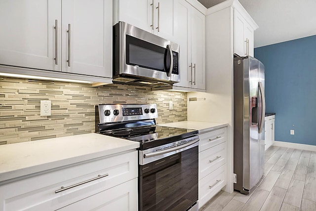 kitchen featuring backsplash, white cabinets, light hardwood / wood-style flooring, and stainless steel appliances