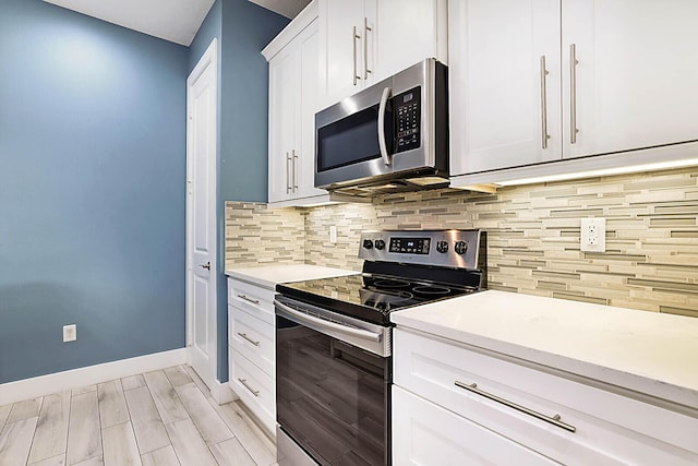 kitchen with backsplash, white cabinets, light wood-type flooring, and appliances with stainless steel finishes