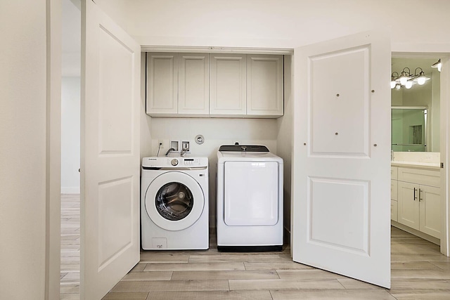 laundry room featuring separate washer and dryer, cabinets, and light wood-type flooring