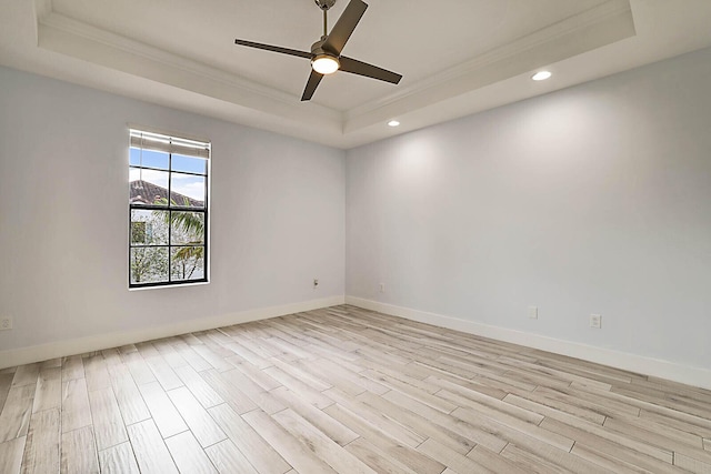 unfurnished room with ornamental molding, light hardwood / wood-style floors, ceiling fan, and a raised ceiling