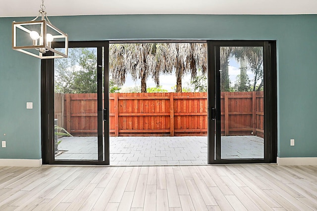 doorway to outside with french doors, a chandelier, and light wood-type flooring