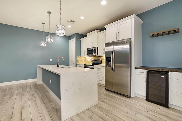 kitchen with white cabinets, stainless steel appliances, wine cooler, sink, and hanging light fixtures