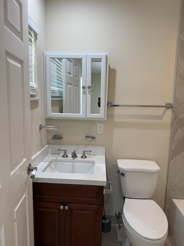 bathroom featuring vanity, a tub to relax in, and toilet