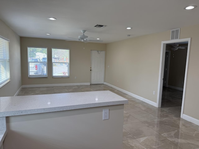 kitchen featuring light stone counters and ceiling fan