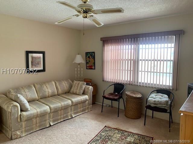 living room with ceiling fan, light colored carpet, and a textured ceiling